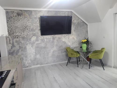 a kitchen with a table and a tv on a wall at Alina apartaments in Sibiu