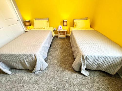 two beds in a room with yellow walls at The Arcade close to downtown with fenced yard in Sanford
