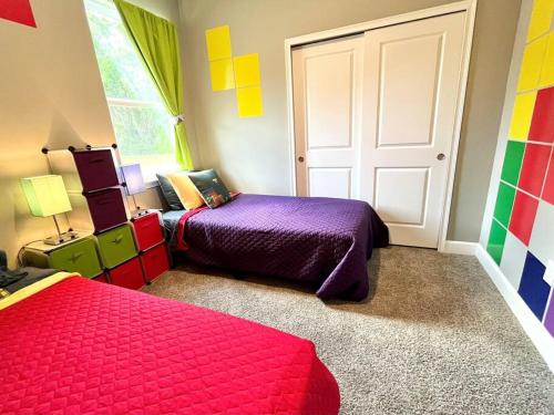 a bedroom with two beds and a door with colorful walls at The Arcade close to downtown with fenced yard in Sanford