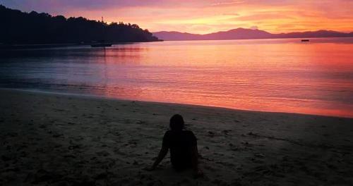 a person sitting on the beach watching the sunset at Westpoint Inn in San Vicente