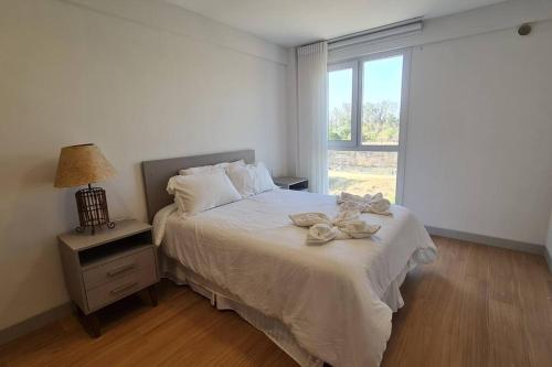 a bedroom with a white bed with a window at Feliz descanso-acogedor/moderno in Tarija