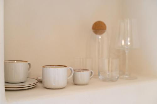 a shelf with three cups and plates and a vase at Church Apartments in Český Krumlov