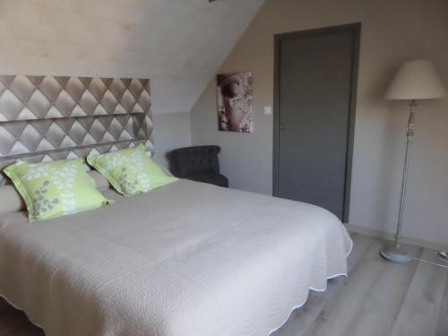 1 dormitorio con 1 cama blanca grande con almohadas verdes en Les Gites de Kerdurod, en Guidel