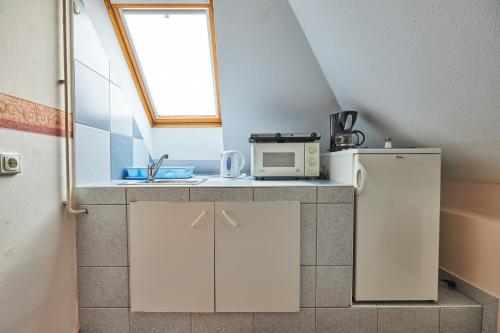 a kitchen with a sink and a microwave at ADA Apartmanház in Hajdúszoboszló
