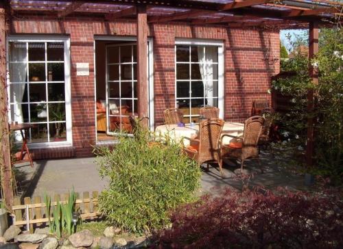 une terrasse avec des chaises et une table en face d'une maison en briques dans l'établissement Komfortables Ferienhaus in Heidmühle mit Terrasse, Garten und Grill, à Schortens