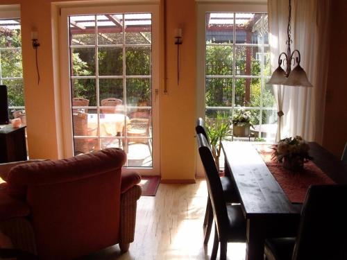 - une salle à manger avec une table, des chaises et des fenêtres dans l'établissement Komfortables Ferienhaus in Heidmühle mit Terrasse, Garten und Grill, à Schortens