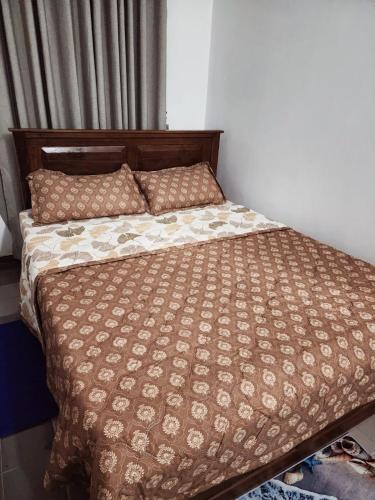 a bed in a bedroom with a brown comforter and pillows at Andrews resident in Katunayake