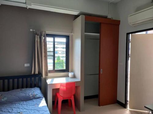 Un dormitorio con una silla roja, una cama y una ventana en Mimi Cozy Apartment- Oldrown Siriraj Wanglang Market en Bangkok
