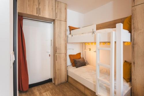 Cette chambre comprend 2 lits superposés et une porte. dans l'établissement Studio Familial Entièrement Rénové Cauterets Centre, à Cauterets
