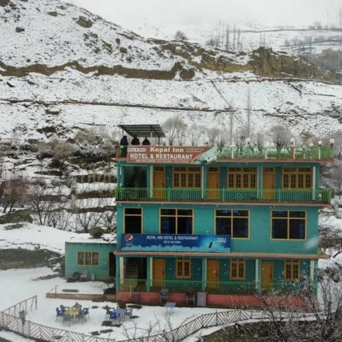 a blue building with people on top of it in the snow at KAPEL Inn HOTEL in Nagir
