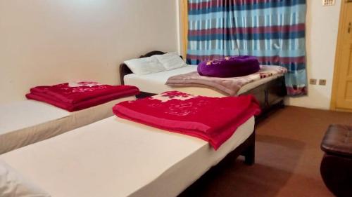 a room with three beds with red blankets on them at KAPEL Inn HOTEL in Nagir