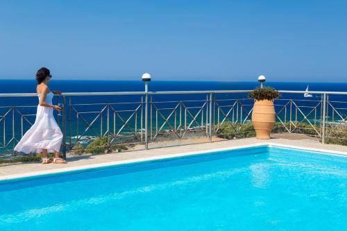 a woman in a white dress standing next to a swimming pool at Amazing sea views at villa Elafonissi with private pool, near Elafonissi beach in Chania