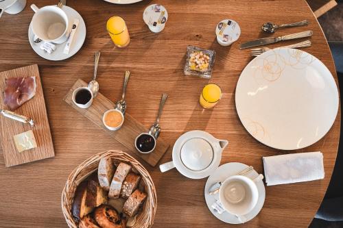 a table with plates and cups of coffee and a basket of food at Logis Hôtellerie Les Brisants , Restaurant J M Perochon in Brétignolles-sur-Mer