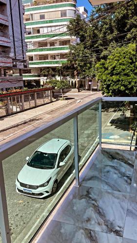 ein weißes Auto, das von einem Balkon aus auf einer Straße geparkt ist in der Unterkunft Dunas Apartamento in Cabo Frio