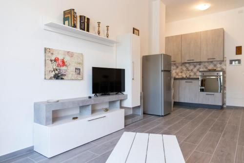 een keuken met witte kasten en een flatscreen-tv bij Gray Pearl - modern apartment in the city center in Arona