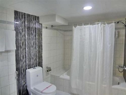 a bathroom with a toilet and a tub and a shower curtain at Furnished Deluxe Private Studio Apartments near Union Metro Station in Dubai