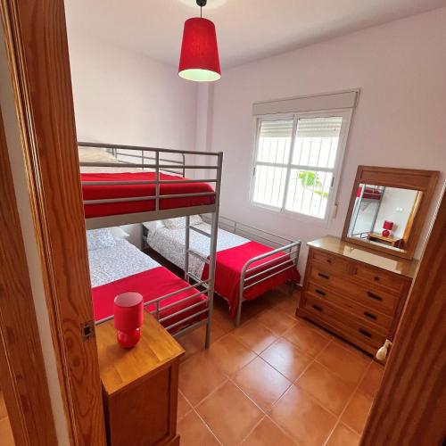 a bedroom with two bunk beds and a mirror at Casa adosada en Urbasur ISLANTILLA in Islantilla
