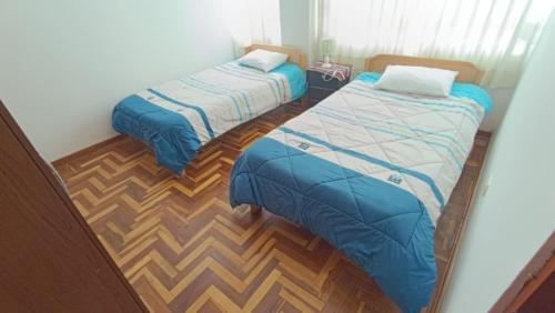 Duas camas num quarto com pisos em madeira em WaskarWasi em Cusco