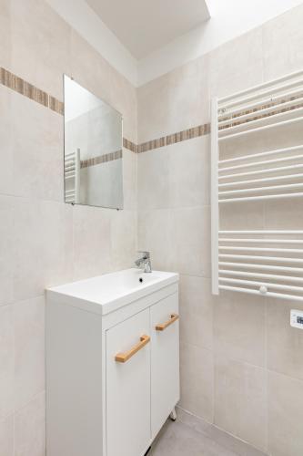 une salle de bain blanche avec un lavabo et un miroir dans l'établissement Bel Appartement climatisé proche Paris et Disneyland, à Saint-Maur-des-Fossés