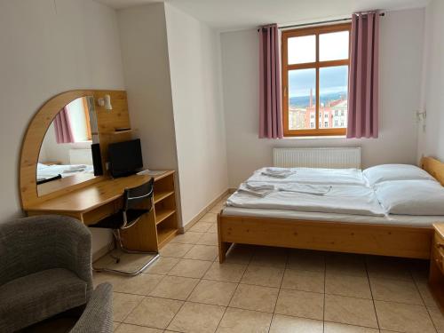 Schlafzimmer mit einem Bett, einem Schreibtisch und einem Spiegel in der Unterkunft Hotel Praha in Broumov