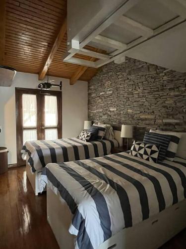 two beds in a room with a stone wall at Agradable cabaña en Tapalpa in Tapalpa