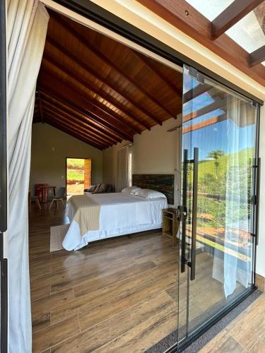 a bedroom with a bed and a sliding glass door at Hotel Fazenda Palmeiras in Rio Casca