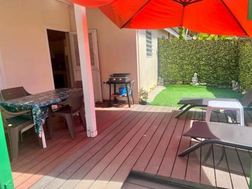 un patio avec un parasol, une table et des chaises dans l'établissement Loc. Ste-Anne, maisonnette plein-pieds 2 à 4 pers., à Sainte-Anne