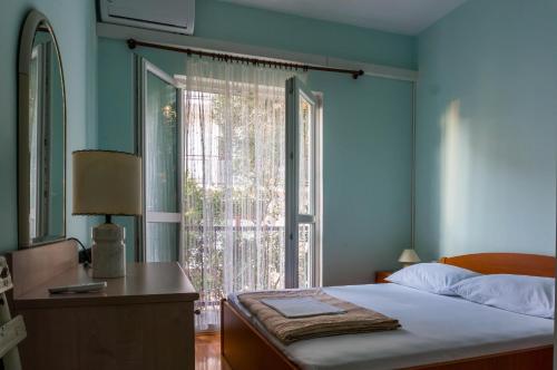 Un dormitorio con una cama y una ventana grande. en Apartman Lili Podgora, en Podgora