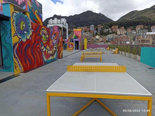 un grupo de mesas de picnic en un edificio con un mural en Casa Campus IVIN Chapinero, en Bogotá