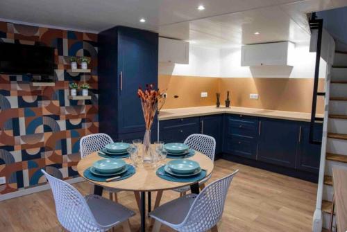 uma cozinha com armários azuis e uma mesa com cadeiras em Maison de village em Chirac