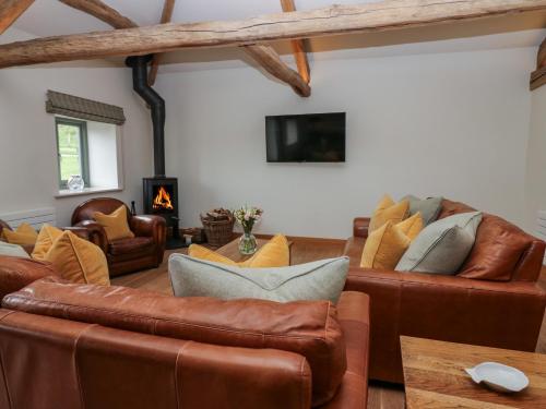 a living room with leather furniture and a tv at Rowan Cottage in Ulverston