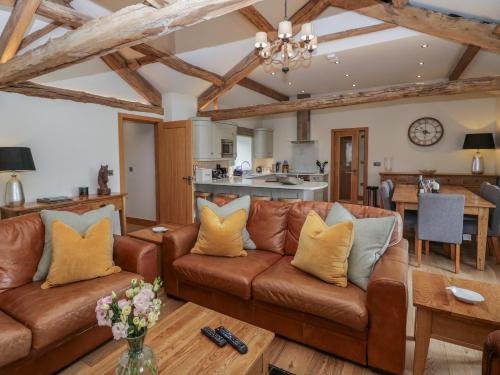 a living room with a brown couch and a kitchen at Rowan Cottage in Ulverston