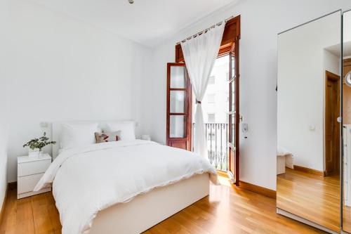 een witte slaapkamer met een groot bed en een glazen deur bij Serrano & Claudio Coello: Lujo, Luz y Elegancia in Madrid