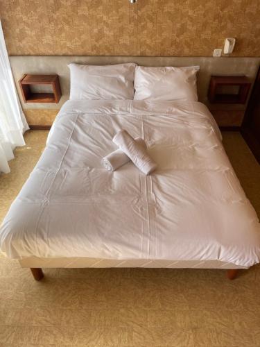 Cama blanca con sábanas y almohadas blancas en Le D'Artagnan - App 5 - Rez-de-chaussée, en Cazaubon