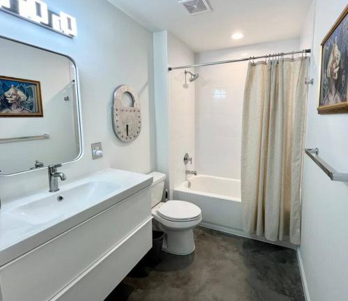 a white bathroom with a toilet and a tub and a sink at The Butterfly House - with sauna in Sanford