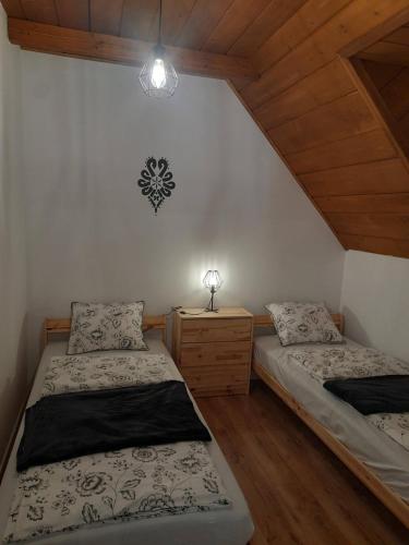a bedroom with two beds and a lamp on the wall at Apartament Kapłonówka in Bańska