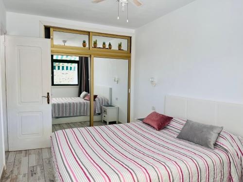 ein weißes Schlafzimmer mit einem Bett und einem Spiegel in der Unterkunft Corona Amarilla Sea View and Relax Puerto Rico in Puerto Rico de Gran Canaria