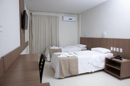 a hotel room with two beds and a table at Oasis Hotel in Cajazeiras