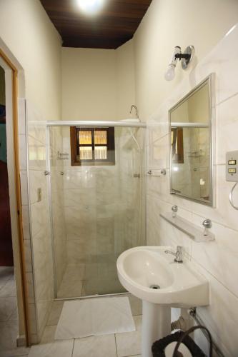 a white bathroom with a shower and a sink at Apoena Chales da Ilha in São Francisco Xavier
