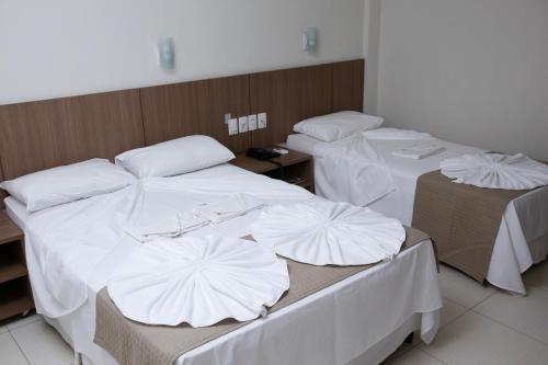 two beds in a room with white covers on them at Oasis Hotel in Cajazeiras