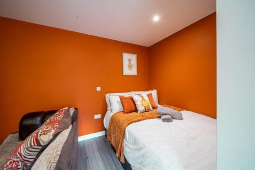 a bedroom with orange walls and a bed and a couch at Corner studio apartment in Sheffield in Sheffield