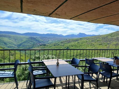 un patio con mesas y sillas y vistas a las montañas en Hotel Rural Porta Coeli - Dehesa Santa Lucía en San Martín del Castañar