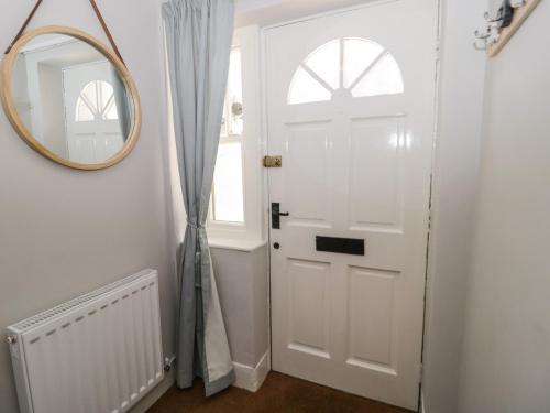 a hallway with a white door and a mirror at Oriel Cottage in Conwy