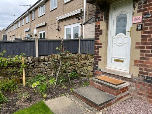 a brick house with a stone wall and a white door at Two Four Four, holiday home in Matlock in Matlock