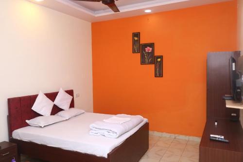 um quarto com uma cama com uma parede laranja em Hotel Ashirwad em Jabalpur