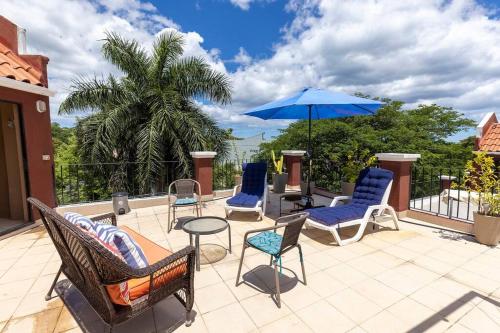 a patio with chairs and a table and an umbrella at Condominio en el Centro de Tamarindo in Tamarindo