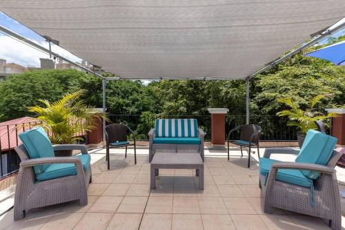 a patio with chairs and tables and an umbrella at Condominio en el Centro de Tamarindo in Tamarindo