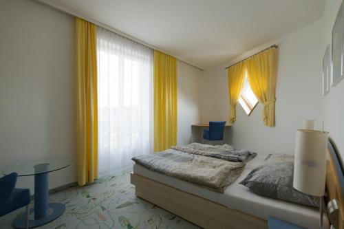 um quarto com uma cama, uma mesa e cortinas amarelas em Château Bernhart 
