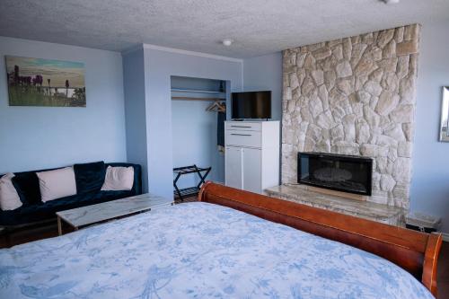 a bedroom with a bed and a stone fireplace at HOV B&B House -Hospitality Ocean View Victoria- in Victoria
