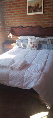 een bed met witte lakens en kussens in een slaapkamer bij Cabañas Don Fernando in Santa Rosa de Calamuchita